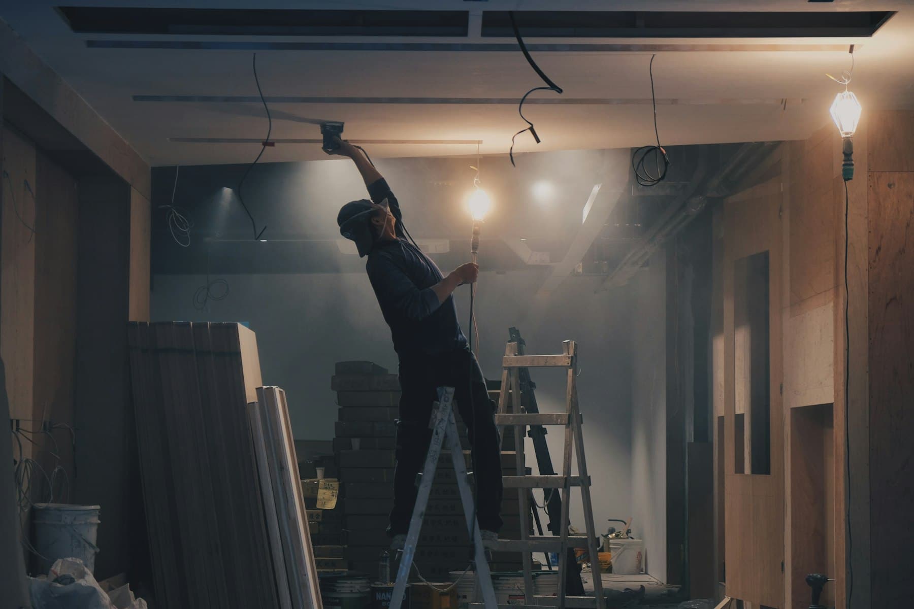 Technician on a step ladder carrying out ceiling work inside a building